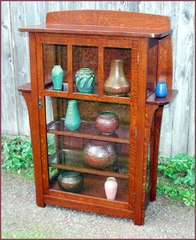 Replica Limbert china cabinet with elongated corbles supporting exterior shelves.